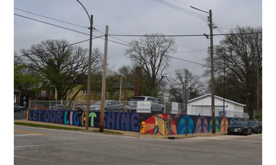 Mural painted on a street corner with the words Let Our Light Shine and a book.