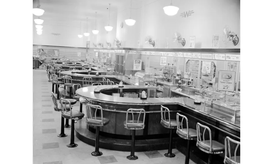 Black and white photo of seats at a series of curved counters.