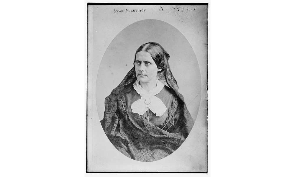 Portrait of a stern-faced woman in lace blouse with parted hair.
